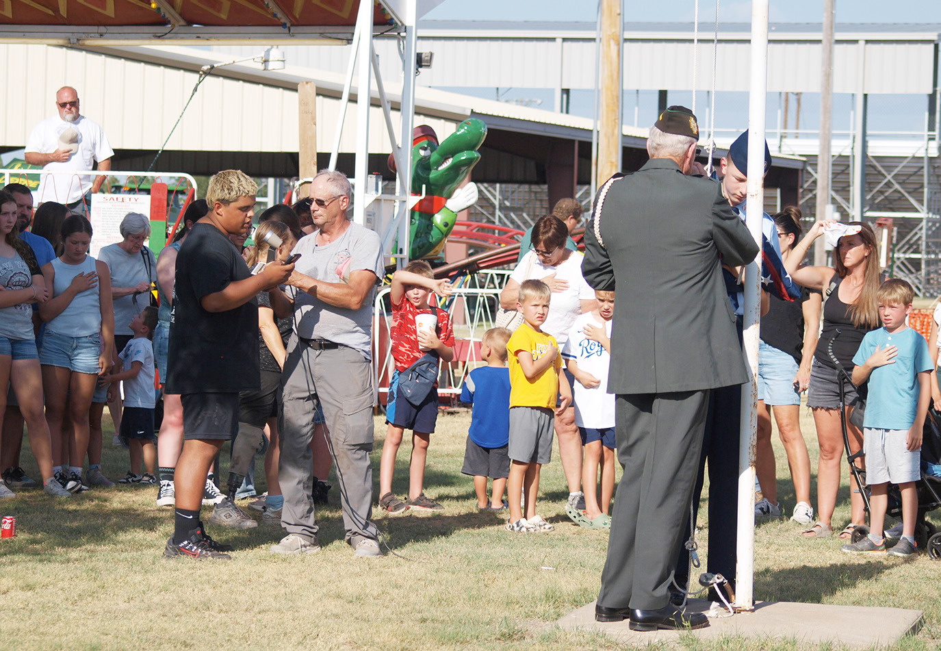 A crowd respectfully looks on as Devon Castillo sings the national anthem as Gary Kreutzer and Theodore Laws (Civilian Air Patrol, Denver) raise the flag.