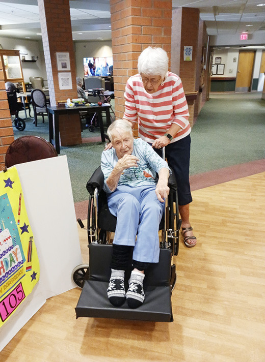 Pat Arfsten guides Eileen Schwindt into position at at her gift and goodies table for her 105th birthday. Provided