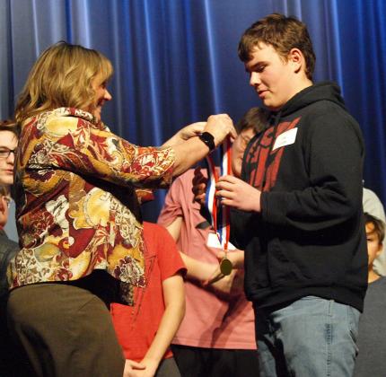 USD 467 Superintendent Lori Maxwell presents the 2024 Wichita County Spelling Bee Champion, Zim Clark, with his first-place medal. Congratulations, Zim!