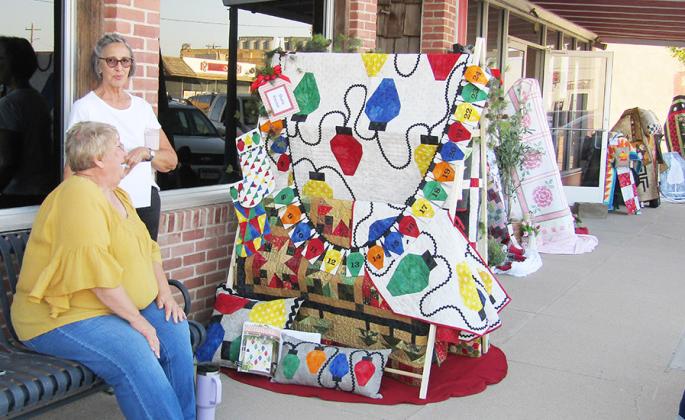 Above: Quilt Guild members Sharla Krenzel and Kathy Mullen display a large assortment of quilts. Below: A recently departed member of the community, Billie Biel, is lovingly remembered.