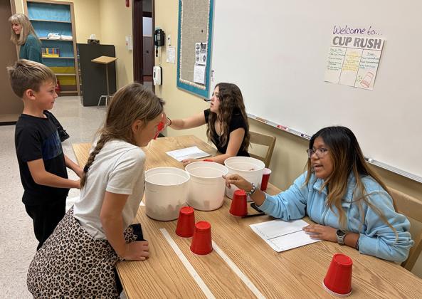Finn Baker and Harlow Horton learn Cup Rush from Jayah Case and Destiny Cibrian. Mrs. Anthony, in the background, visits the various game tables.