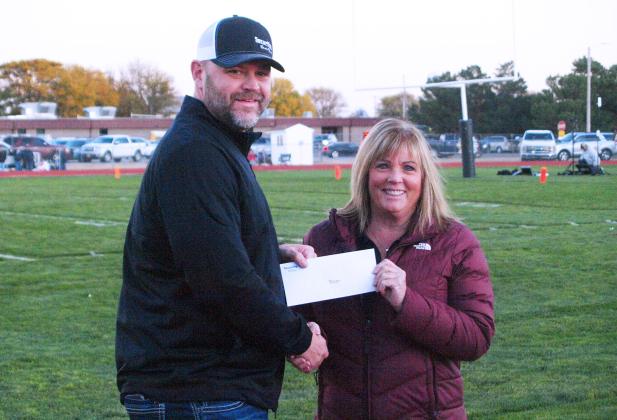 Security State Bank Senior Vice President Josh Young presents a check with proceeds from the bank's football tailgates to USD 467 Superintendent Lori Maxwell. (Staff photo)
