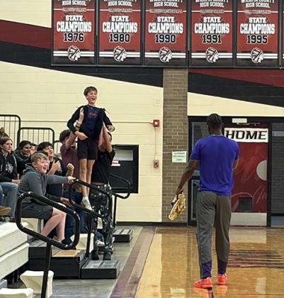Junior High classmates hold Jack Ricke above the crowd to enhance his chances of winning tickets to the game in Tribune and a Harlem Wizards jersey.