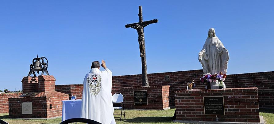 Above: Fr. Felix conducts the dedication and blessing of the new bronze crucifix at St. Mary Cemetery.