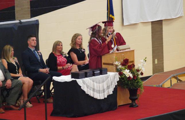 At the Podium (L-R): Salutatorian Jentri Porter and Valedictorian Delaney Biel. Seated (in frame) on the stage: Board of Education President Eryka Smith, WCJSHS Principal Brant Douglas, Superintendent Lori Maxwell, Mrs. Bridgette Carpenter.