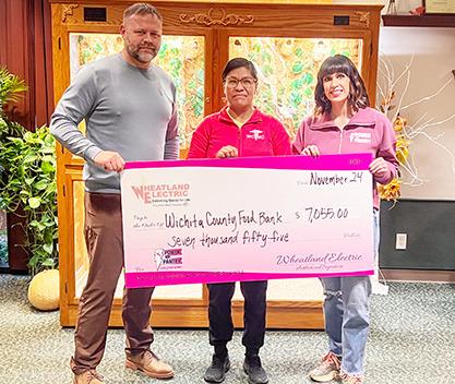 Alli Conine (right), director of member services and corporate communications at Wheatland Electric, and Josh Young, trustee (left), present a check for $7,055 to Mirna Jimenez (center) of the Wichita County Food Bank. Provided