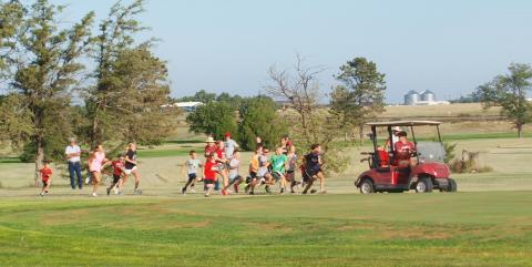 Coach Tankersley makes sure none of the kids fall too far behind in the Fun Run at the Leoti Invitational Cross Country Meet on Sept. 5.