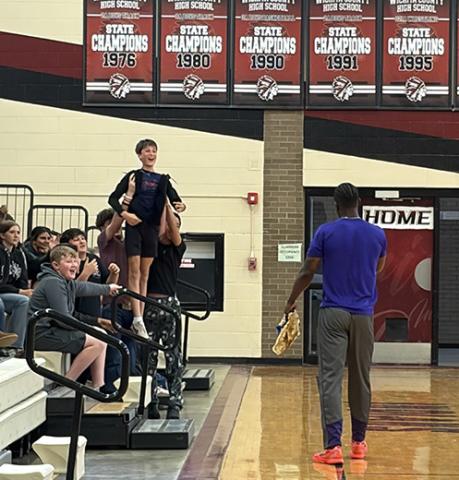Junior High classmates hold Jack Ricke above the crowd to enhance his chances of winning tickets to the game in Tribune and a Harlem Wizards jersey.