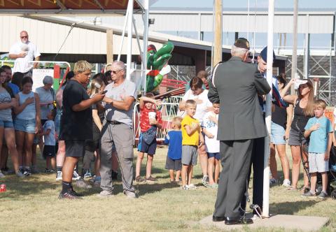 A crowd respectfully looks on as Devon Castillo sings the national anthem as Gary Kreutzer and Theodore Laws (Civilian Air Patrol, Denver) raise the flag.
