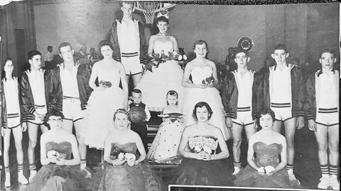 [ Above:] Sara Herndon reigns as Wichita County Community High School cage queen at Leoti. Pictured with her are JoEllyn Jaeger, Carol Seibel, Donna Wewer, Loula Mae Schwindt, Phyllis Humble, Alice Pfeifer, Delbert Harkness, Rolly Brown, Eddie Kessler, Capt. J.R. Royer, Jerry Hooker, Larry Schwindt, and Larry appl. Tiny attendants bearing the insignia of authority in the extravaganza are Gary Wewer and Kim Green.