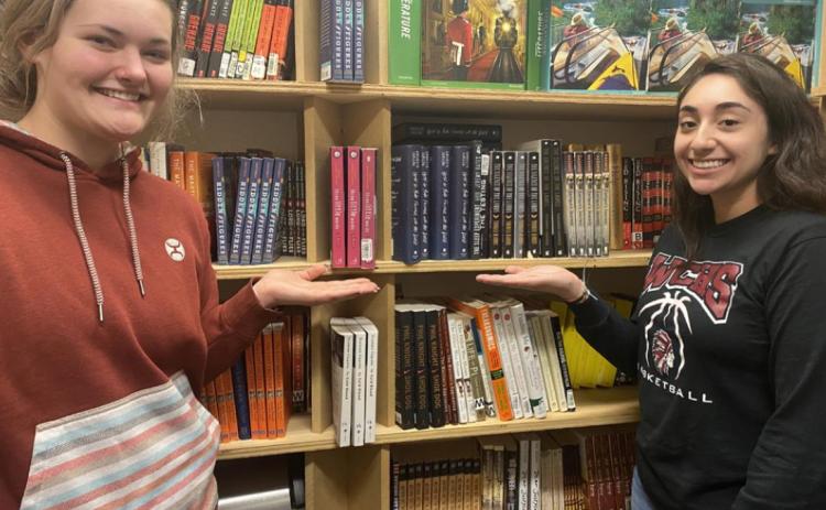 Brooklyn Burch and Genesis Ponce pose with just a few of the books the English department has been able to purchase with grant funds.