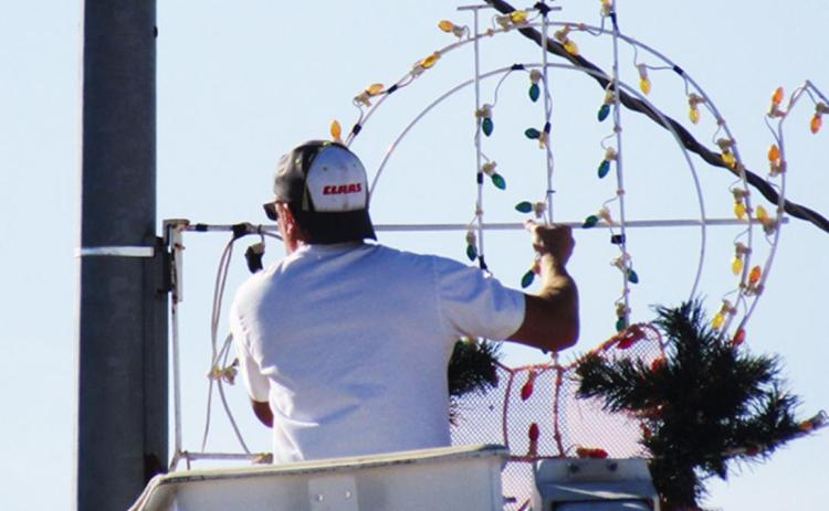 Pictured above: City Superintendent Travis Seaton affixes a wreath to a light pole downtown.