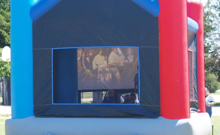 No, that's not a movie being played in the bouncy house. It fooled me, too. Could have been cool, though.