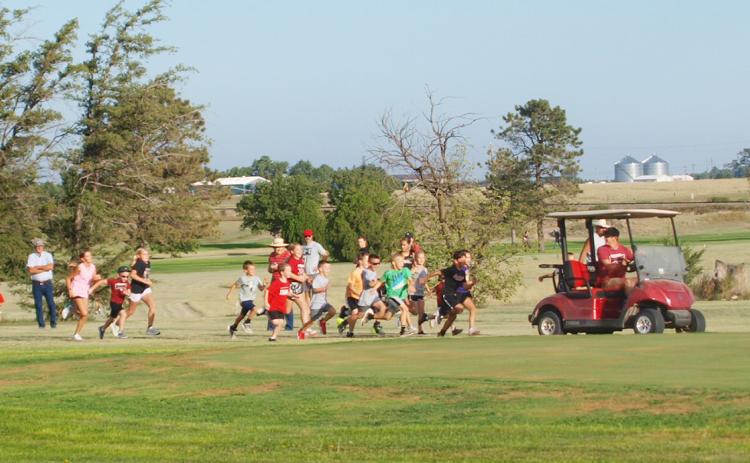Coach Tankersley makes sure none of the kids fall too far behind in the Fun Run at the Leoti Invitational Cross Country Meet on Sept. 5.