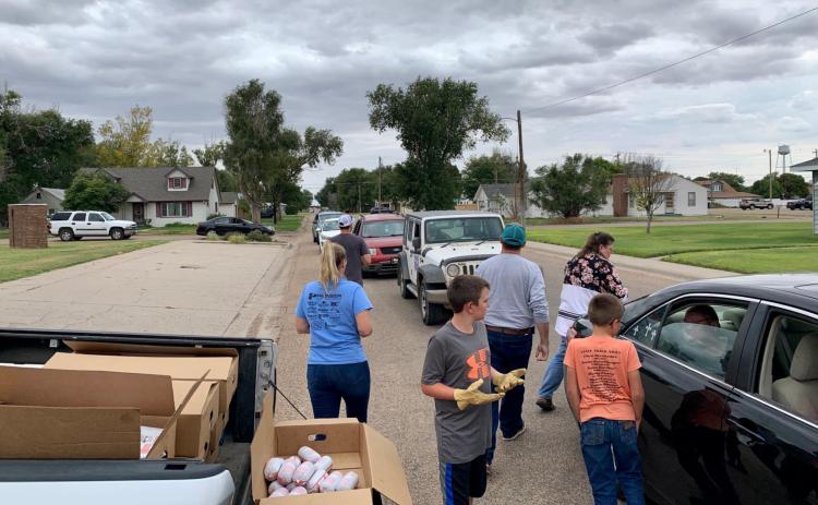 Above: Community members volunteer to pass out the 5-pound packages of ground beef to Wichita Countians who queue around the block to receive their portion of the generous donation. Below: Boxes of tubes of frozen ground beef await distribution.
