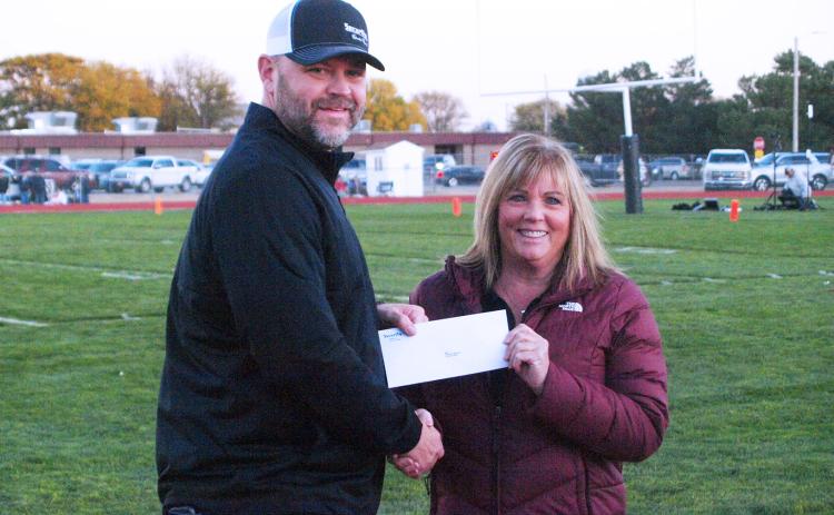 Security State Bank Senior Vice President Josh Young presents a check with proceeds from the bank's football tailgates to USD 467 Superintendent Lori Maxwell. (Staff photo)