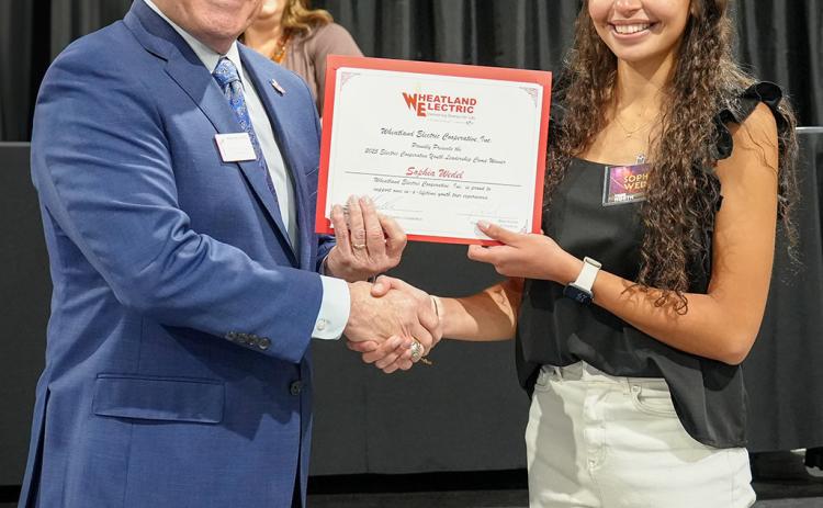 At Right: Bruce W. Mueller (left), CEO/general manager of Wheatland Electric Cooperative, Inc., recognizes Sophia Wedel (right), a junior from Wichita County High School, at WEC’s annual meeting in Scott City. Wedel was selected to represent Wheatland Electric Cooperative, Inc. (WEC) at this year’s Electric Cooperative Youth Tour in Washington, D.C.