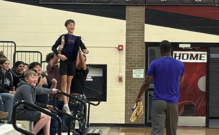 Junior High classmates hold Jack Ricke above the crowd to enhance his chances of winning tickets to the game in Tribune and a Harlem Wizards jersey.