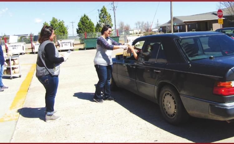 Pictured above, USD 467 employees Teressa Ricke, Nayeli Garcia, and Tammy Mason dispense sack meals to the parent of a district student. –Staff Photo