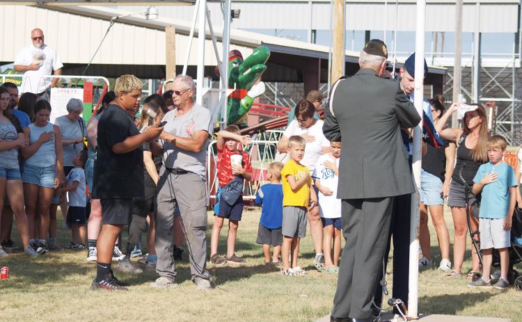 A crowd respectfully looks on as Devon Castillo sings the national anthem as Gary Kreutzer and Theodore Laws (Civilian Air Patrol, Denver) raise the flag.