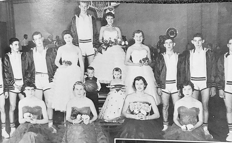 [ Above:] Sara Herndon reigns as Wichita County Community High School cage queen at Leoti. Pictured with her are JoEllyn Jaeger, Carol Seibel, Donna Wewer, Loula Mae Schwindt, Phyllis Humble, Alice Pfeifer, Delbert Harkness, Rolly Brown, Eddie Kessler, Capt. J.R. Royer, Jerry Hooker, Larry Schwindt, and Larry appl. Tiny attendants bearing the insignia of authority in the extravaganza are Gary Wewer and Kim Green.