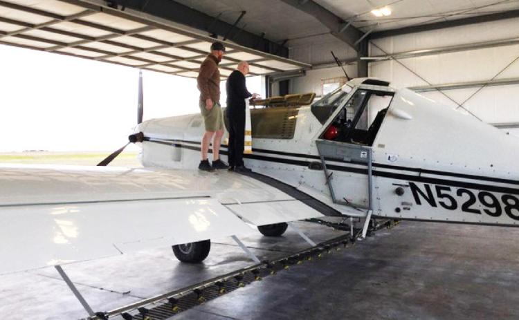 Father Tim Hickey blesses the water in the nose of Ben McNary’s plane prior to take-off. McNary loaded 500 gallons of water into his sprayer for the holy water blessing.